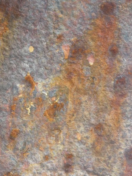Rusted metal texture, formed into a rough, uneven surface in various hues of blue, yellow and red.